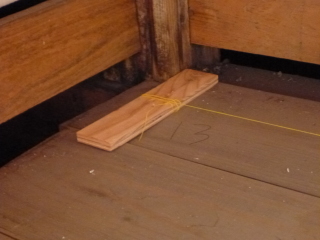 合板の切れ端に水糸を巻き付けて床に固定する